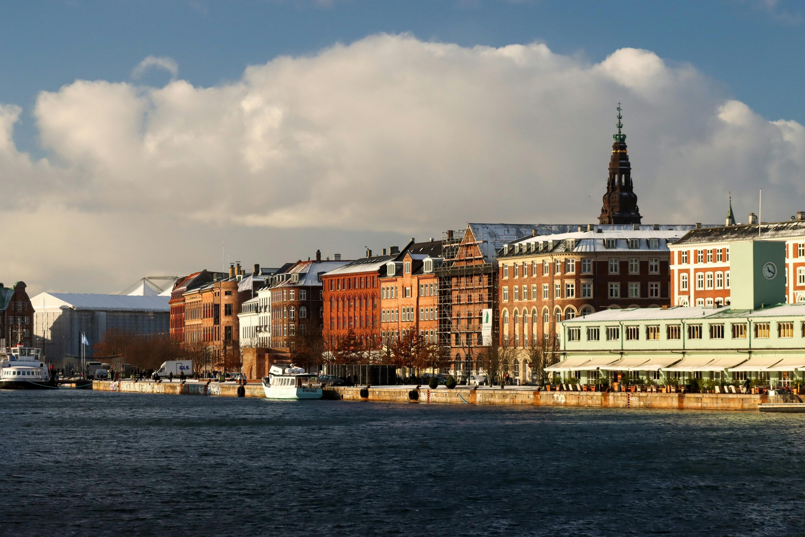 View of Copenhagen's waterfront with historic buildings under a cloudy sky.